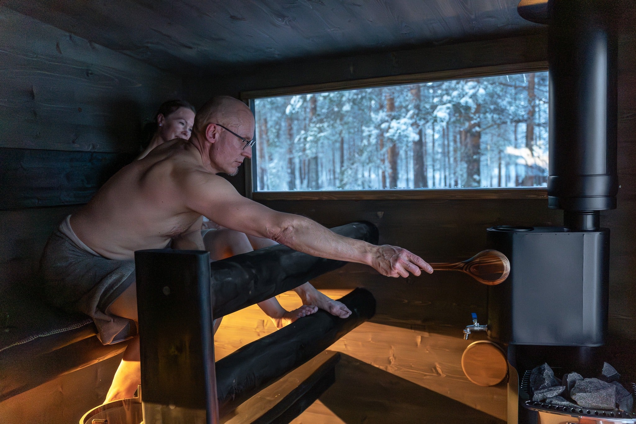 Man kastar löyly på vedkaminen i bastun i Lapelland Sauna XL