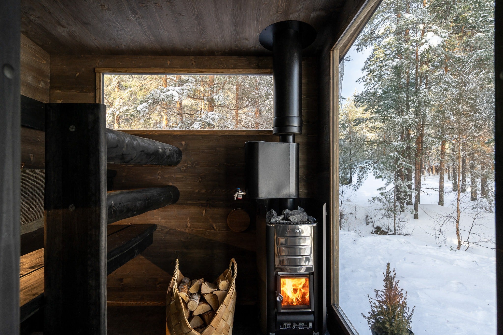 Vedkamin med vedkorg i bastun i Lapelland Sauna XL